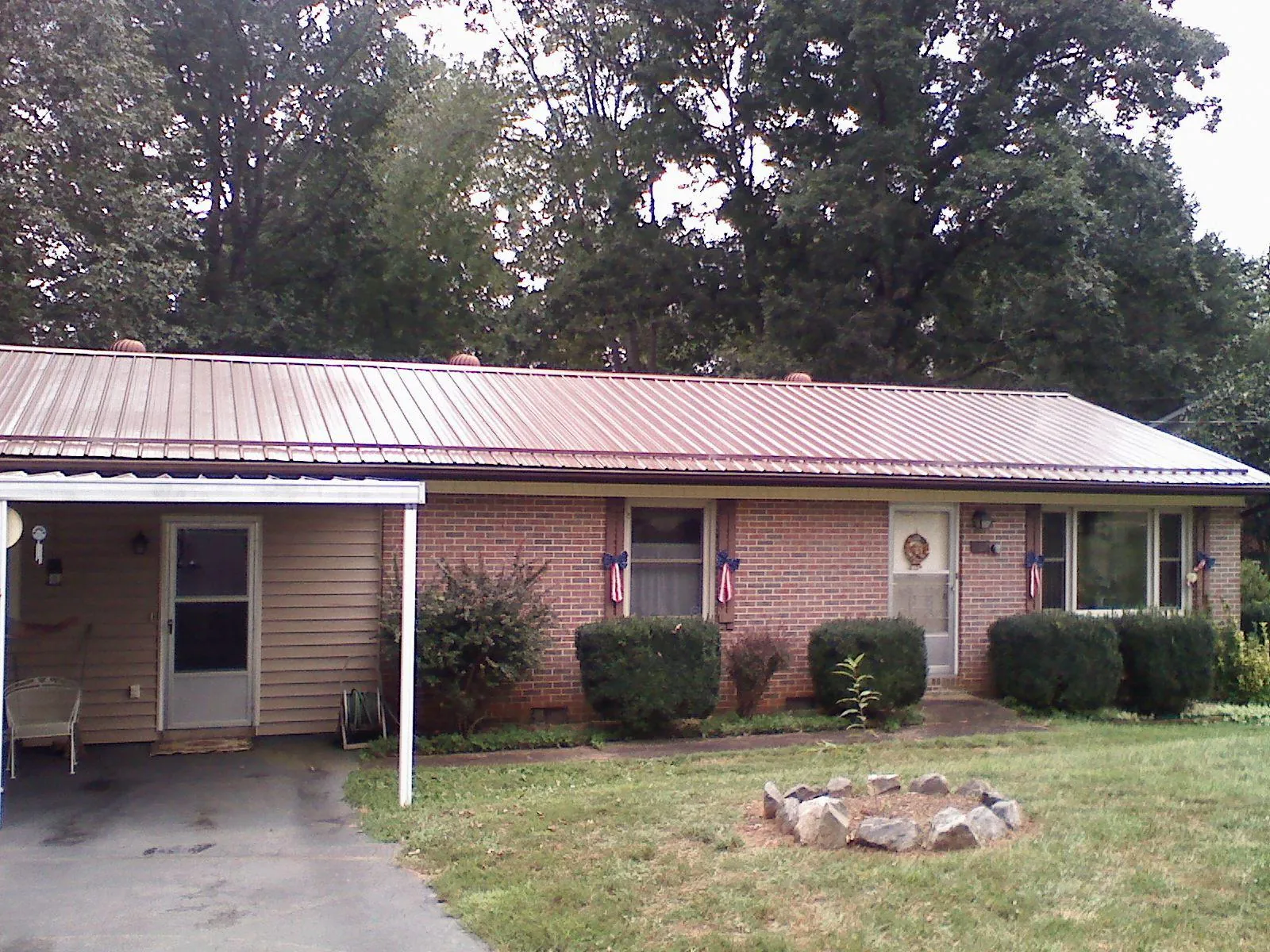 Bronze metal roof and carport on a brick ranch home — Roof Repair work by our crew in Bradyville
