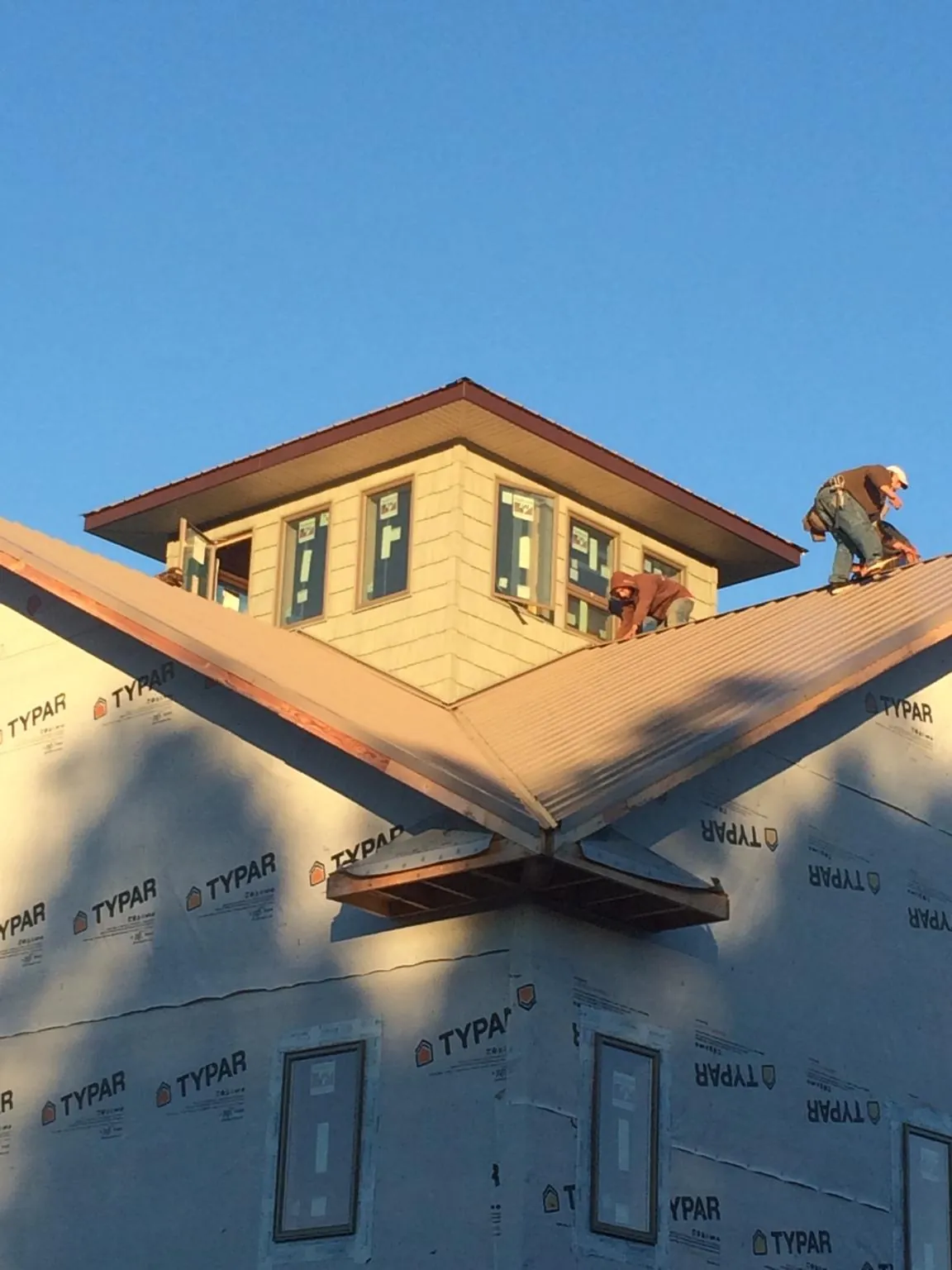 Roofers working around a rooftop cupola on a new metal roof at sunset — Roof Waterproofing in Bradyville by Roofing Brothers